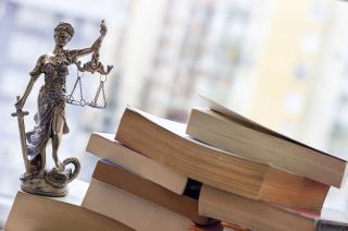 Lady Justice figure beside a pile of books