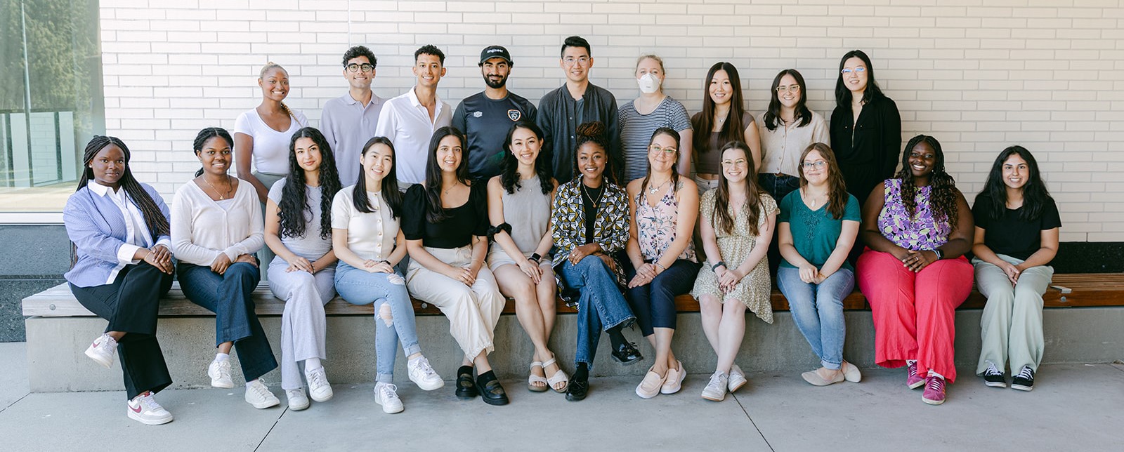 group photo of students sitting and smiling on a bench