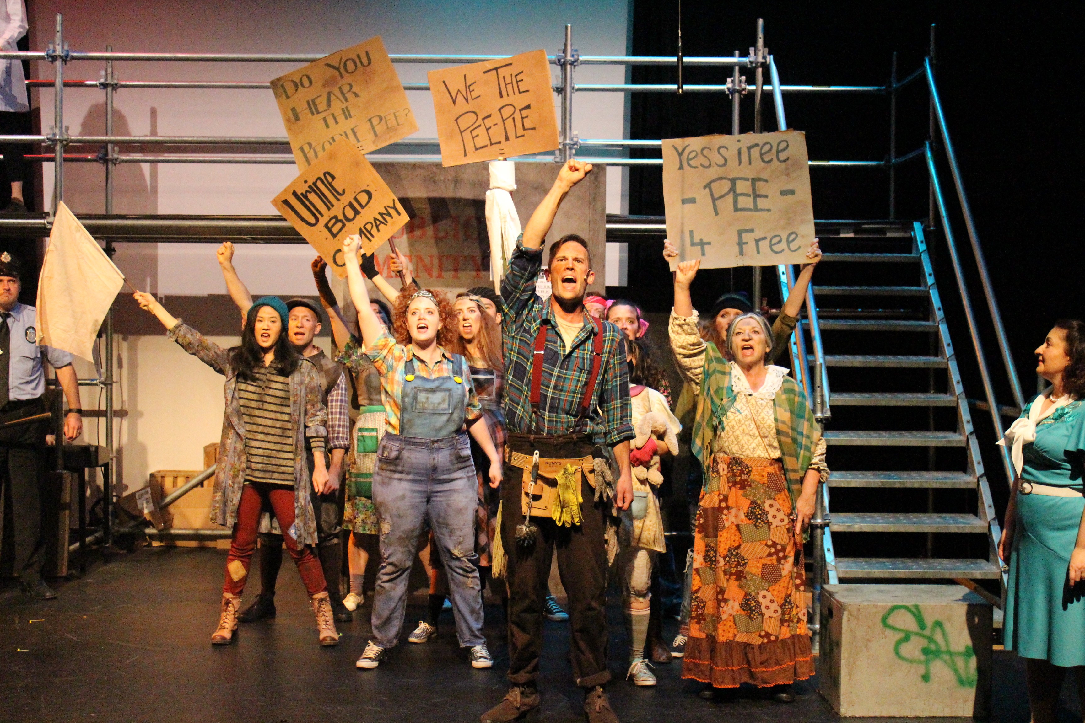 Actors and actresses in dirty costumes perform in Urinetown.