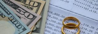 Wedding rings and money on top of a monthly bill