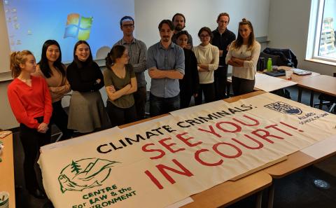 Allard students stand behind banner reading "Climate Criminals: See you in court"