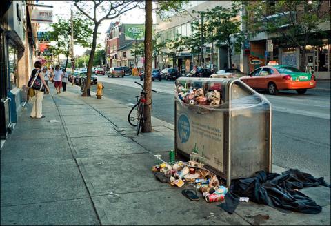 A garbage receptacle overflowing with trash on a street in Toronto. Photo by Sam Javanrouh.