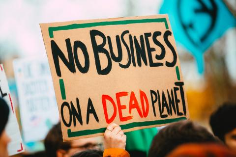 Protester holding sign reading "No business on a dead planet"