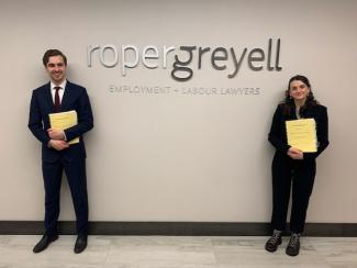 2 students standing beside Roper Greyell signage