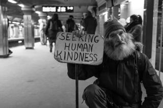 man with sign reading "seeking human kindness"