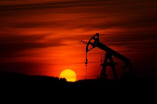 oil drilling silhouetted by red sunset behind